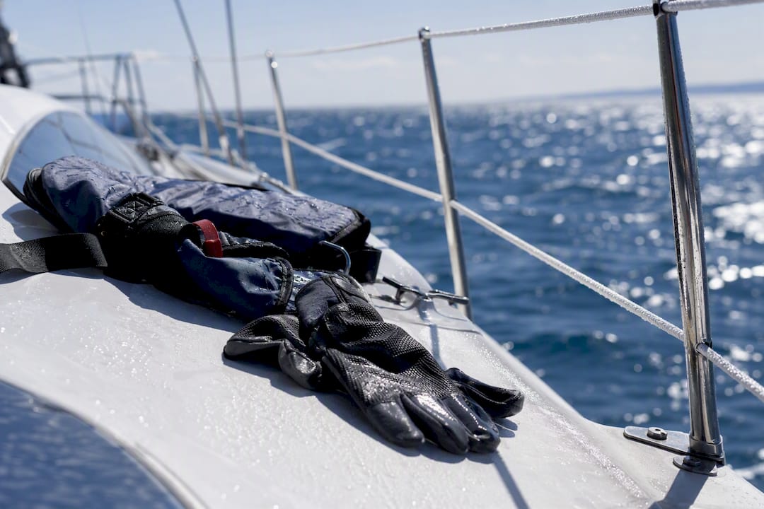 Wet sailboat deck with life jacket and gloves