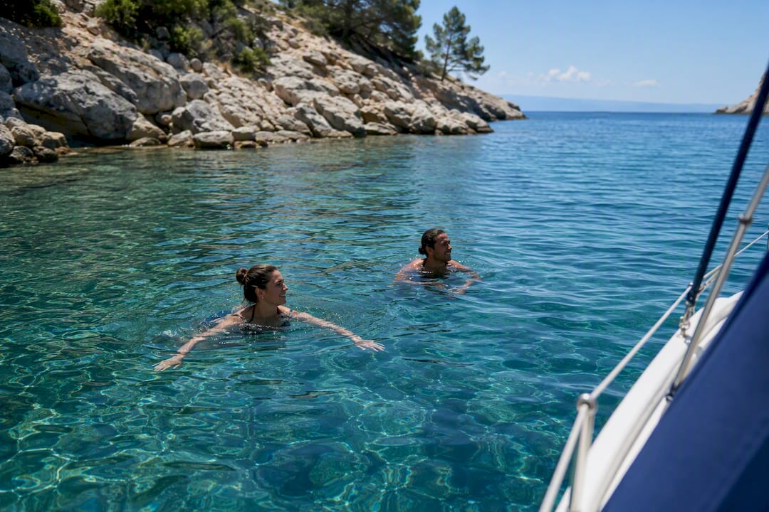 Couple swimming beside sailing boat cove