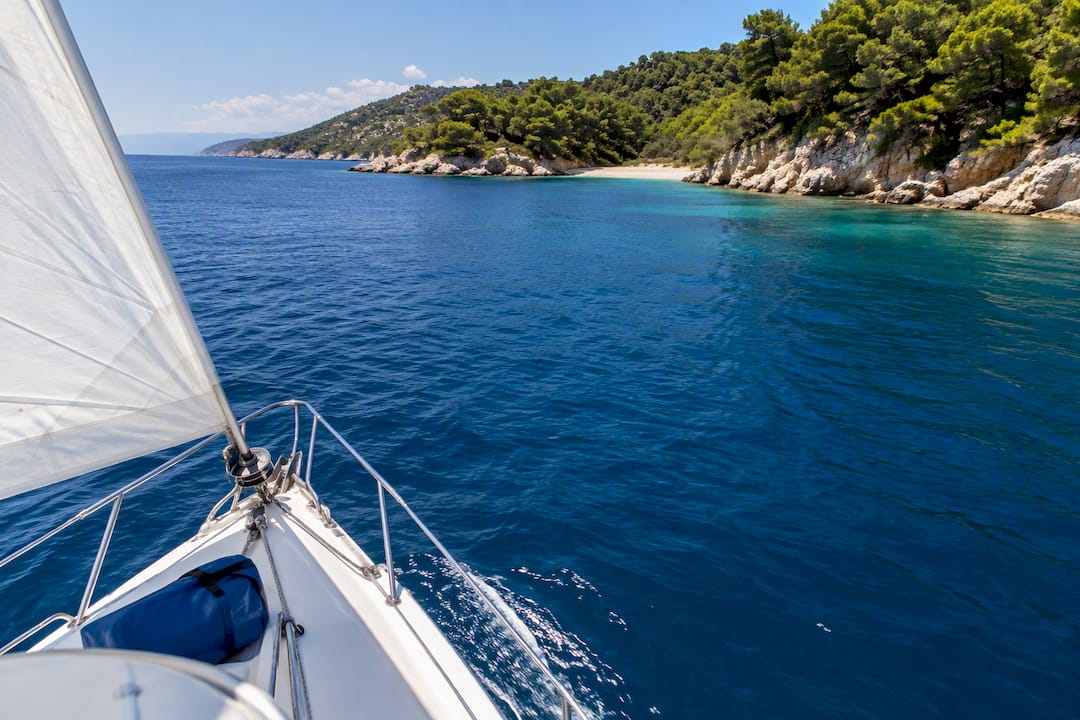Sailing boat approaching a secluded Halkidiki cove