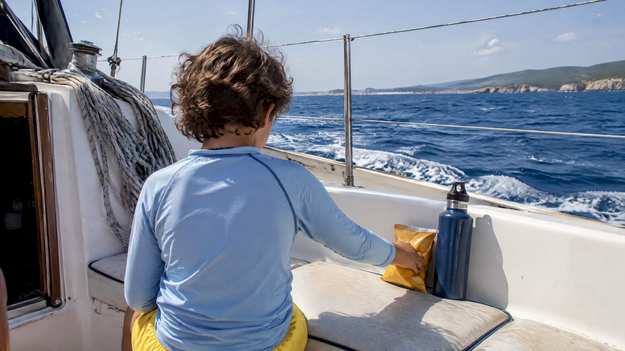 Child organizing snacks aboard sailing boat