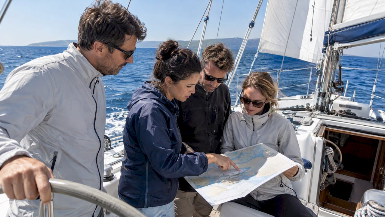 Colleagues study a chart aboard a sailing boat Colleagues study a chart aboard a sailing boat