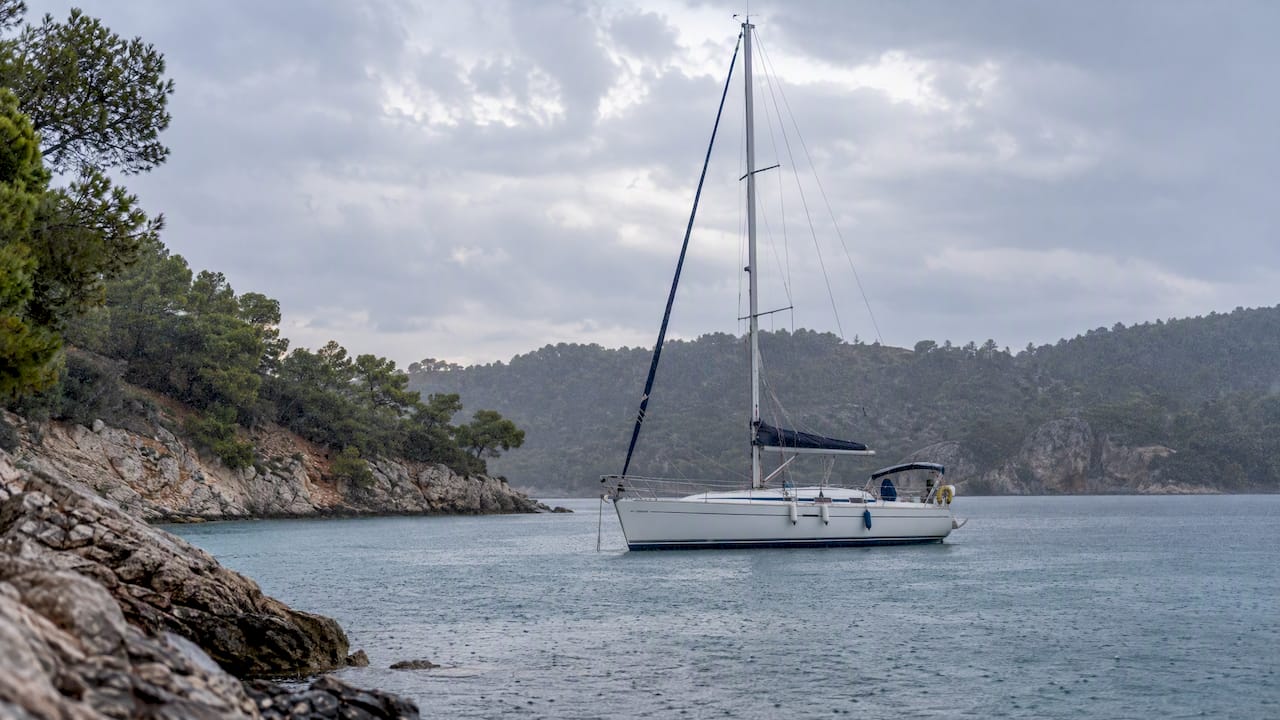 Sailing boat anchored in a rainy sheltered cove
